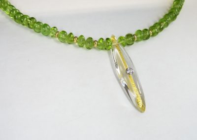 Steinkette Peridot mit einem Glasanhänger Navetteform, in den ein Feingoldstreifen und ein Brillant in einer Weißgoldfassung eingearbeitet sind